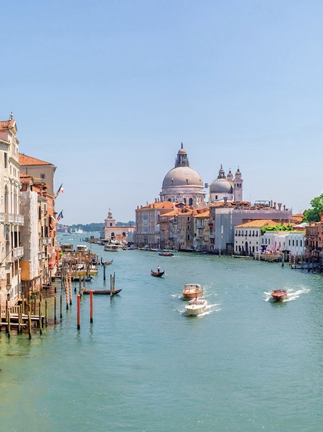 Water bus on Venice Grand Canal with historic buildings and Santa Maria della Salute in the background.