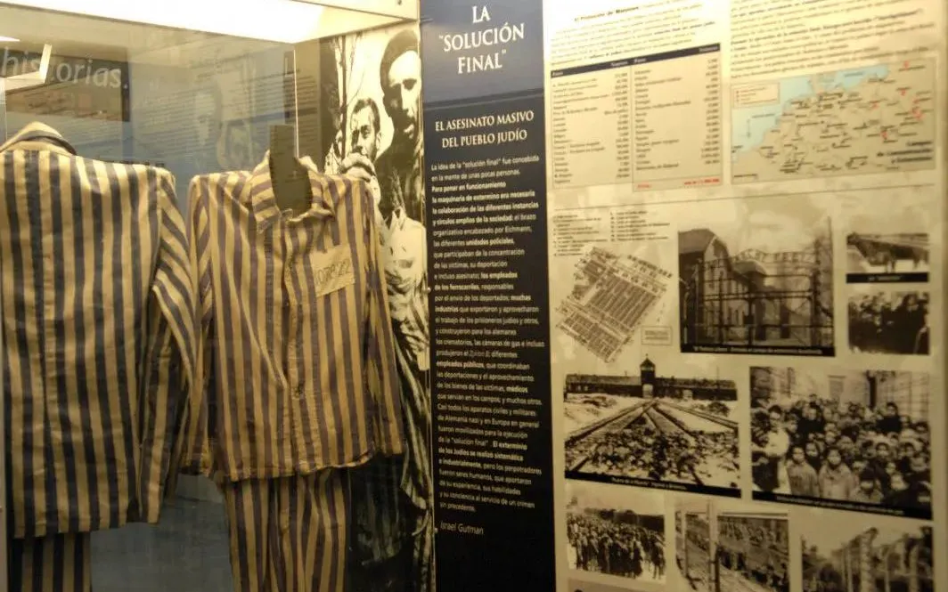 Holocaust exhibit with striped uniforms and historical photos in Buenos Aires museum.