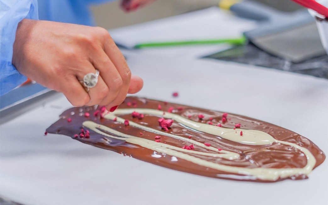 Liquid chocolate being spread with toppings at Chocolate Story Museum Porto.