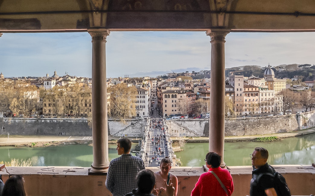 View of Rome from Castel Sant'Angelo terrace with people overlooking the Tiber River and cityscape.