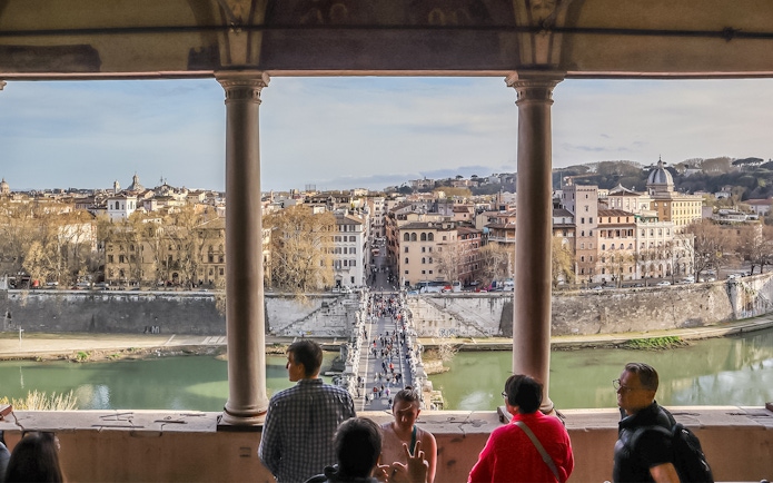 View of Rome from Castel Sant'Angelo terrace with people overlooking the Tiber River and cityscape.