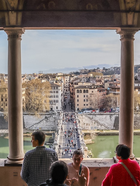 View of Rome from Castel Sant'Angelo terrace with people overlooking the Tiber River and cityscape.