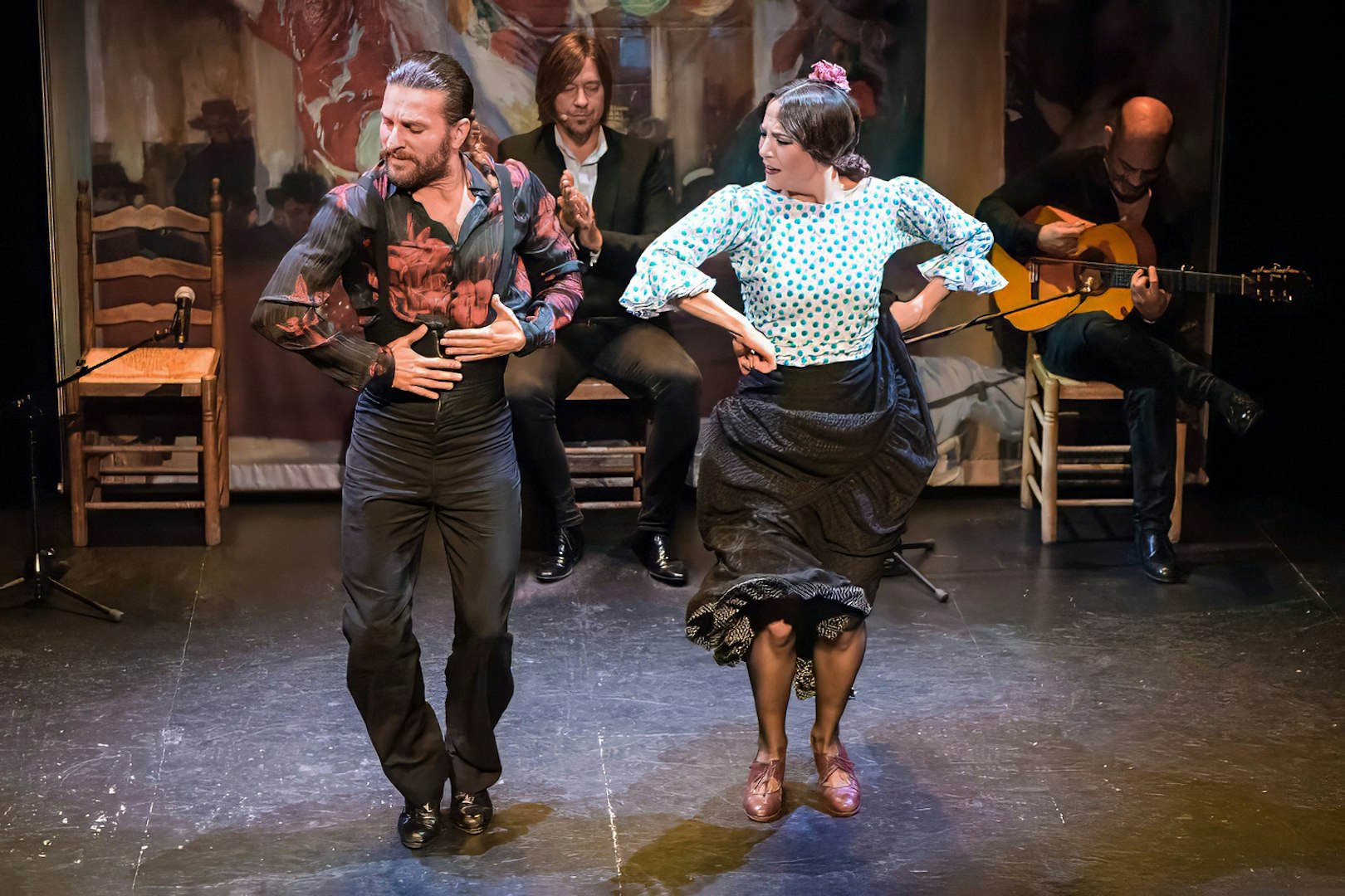 Flamenco dancers performing at Teatro Flamenco Triana with musicians in the background.