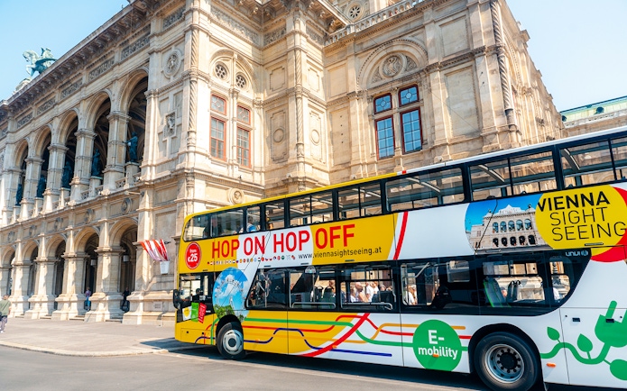 Vienna sightseeing hop-on hop-off bus in front of historic building.