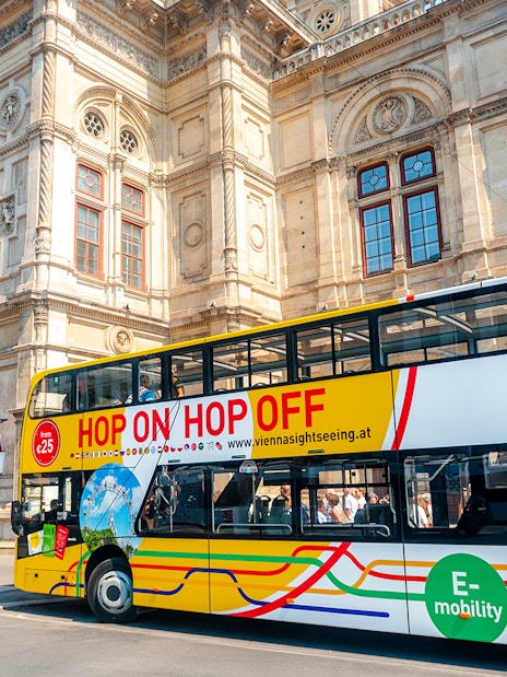 Vienna sightseeing hop-on hop-off bus in front of historic building.