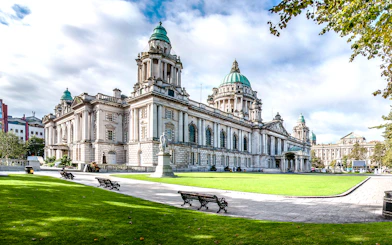 Belfast City Hall with green domes and surrounding gardens, part of Dublin to Giants Causeway tour.