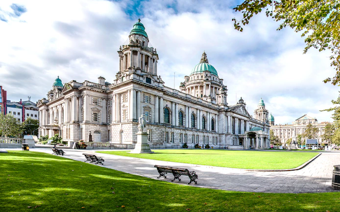 Belfast City Hall with green domes and surrounding gardens, part of Dublin to Giants Causeway tour.