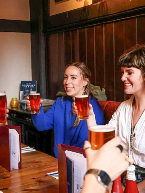 Group enjoying pints at a London pub on the Heart of 'The City' Food Tour.