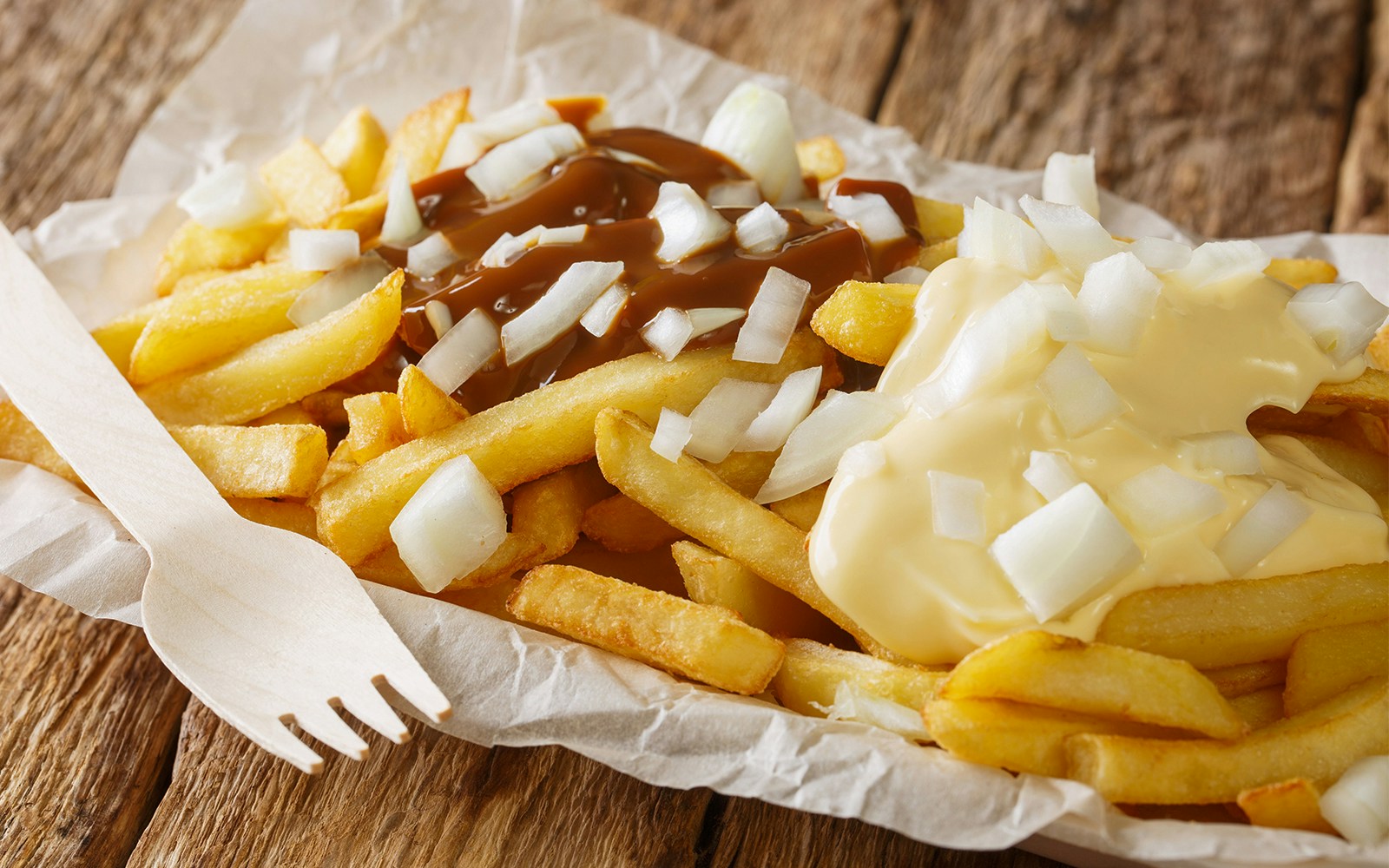 Dutch fries with Patatje oorlog, topped with onions, peanut sauce, and mayonnaise.
