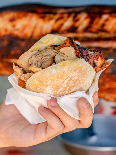 Hand holding a traditional Portuguese bifana pork sandwich.