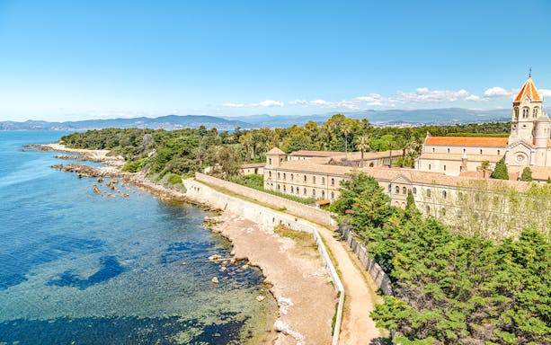 Aerial view of the monastery on Saint-Honorat Island, France, with coastline and trees.