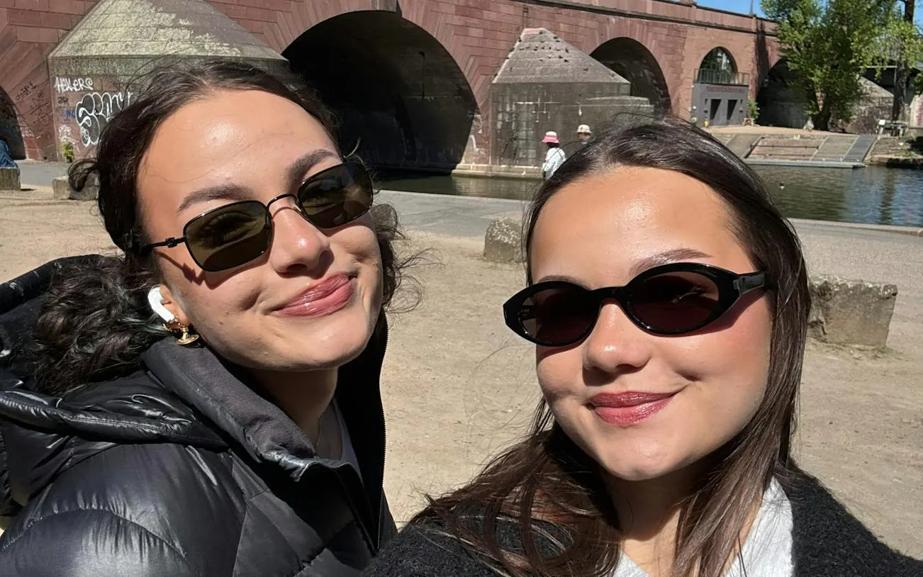 Two people smiling near the historic Alte Brücke bridge in Frankfurt, Germany.