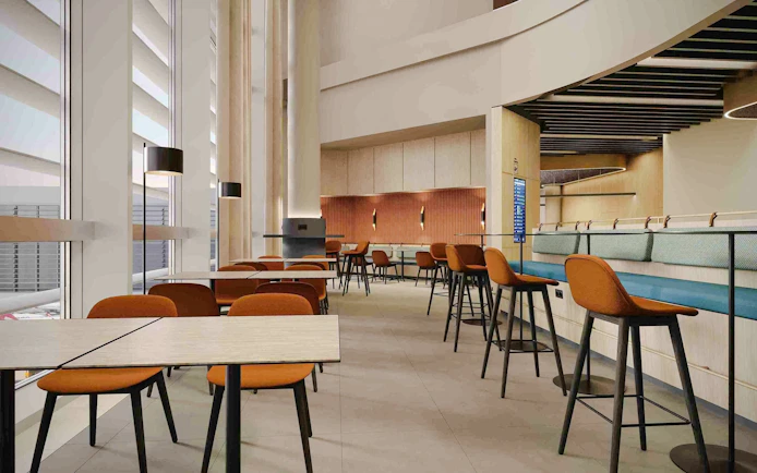 Munich Airport T1 non-Schengen lounge seating area with tables and chairs.