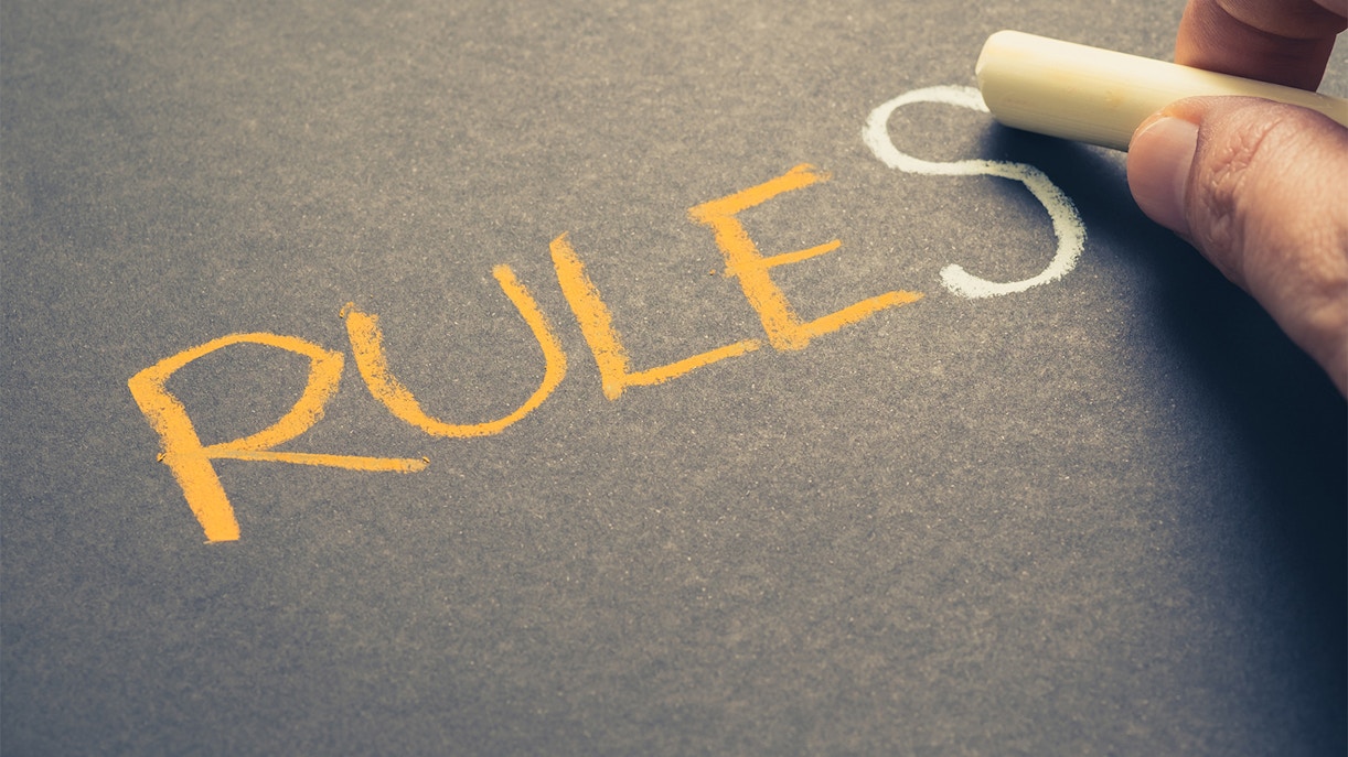 Hand writing "rules" with chalk on a blackboard.
