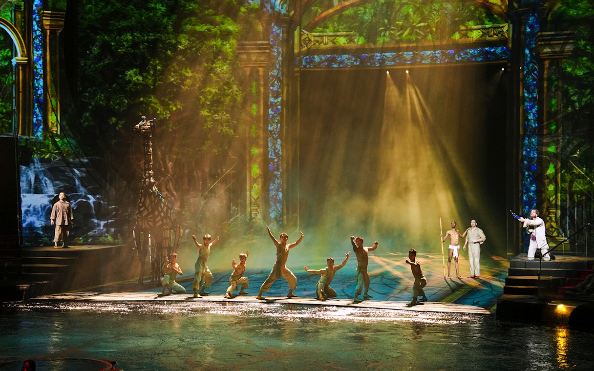 Performers on stage during House of Dancing Water show with vibrant backdrop.