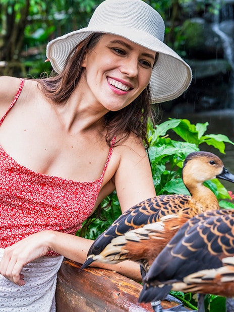 Woman smiling at ducks by a pond at Birdworld Kuranda.