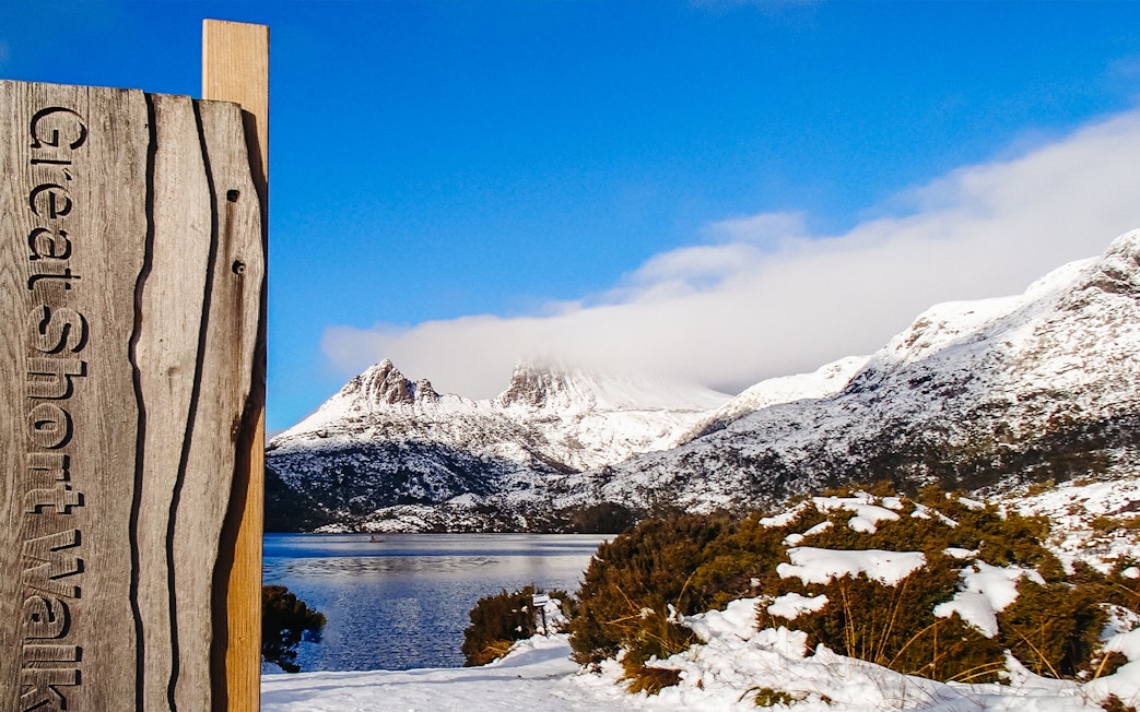 Cradle Mountain view with snow-covered peaks and lake, sign for Great Short Walk.