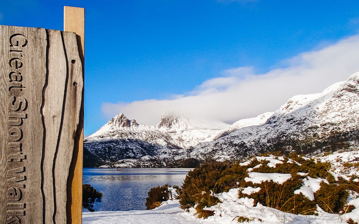 Cradle Mountain view with snow-covered peaks and lake, sign for Great Short Walk.