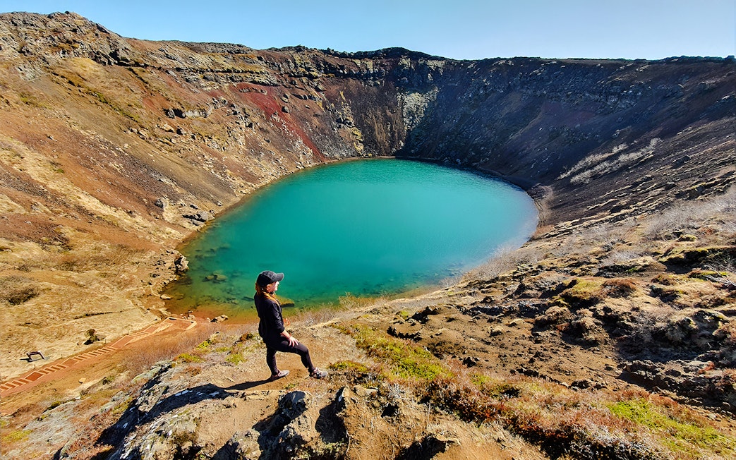Person overlooking Kerid Crater's turquoise water, Golden Circle, near Reykjavik.