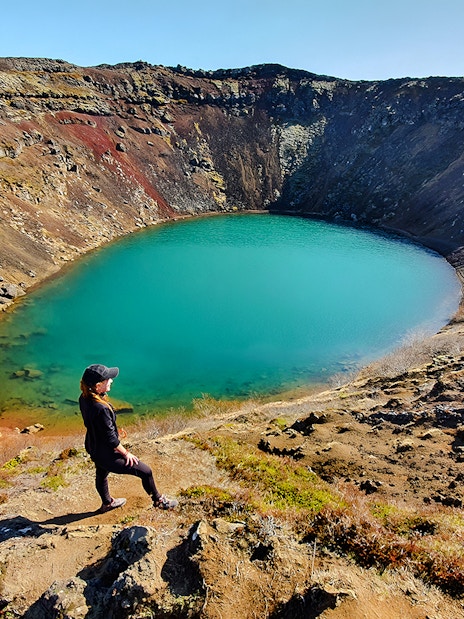 Person overlooking Kerid Crater's turquoise water, Golden Circle, near Reykjavik.