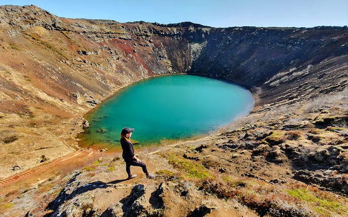 Person overlooking Kerid Crater's turquoise water, Golden Circle, near Reykjavik.