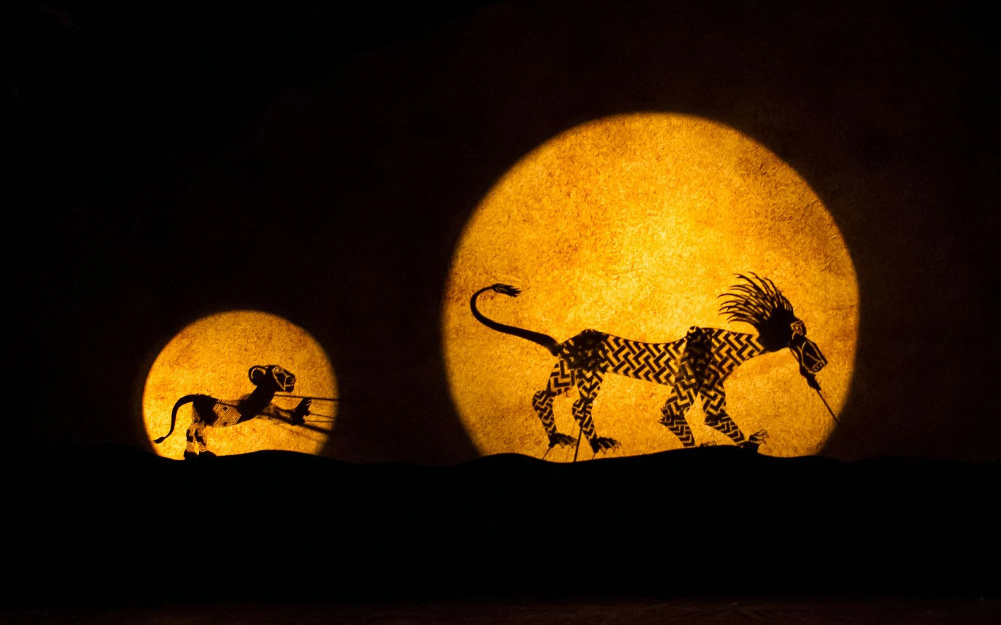 Silhouettes of animals in "The Lion King" stage show against a glowing backdrop.