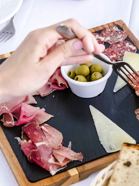 Cured meats and cheese platter with olives and bread on a table.