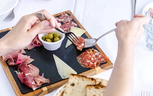 Cured meats and cheese platter with olives and bread on a table.