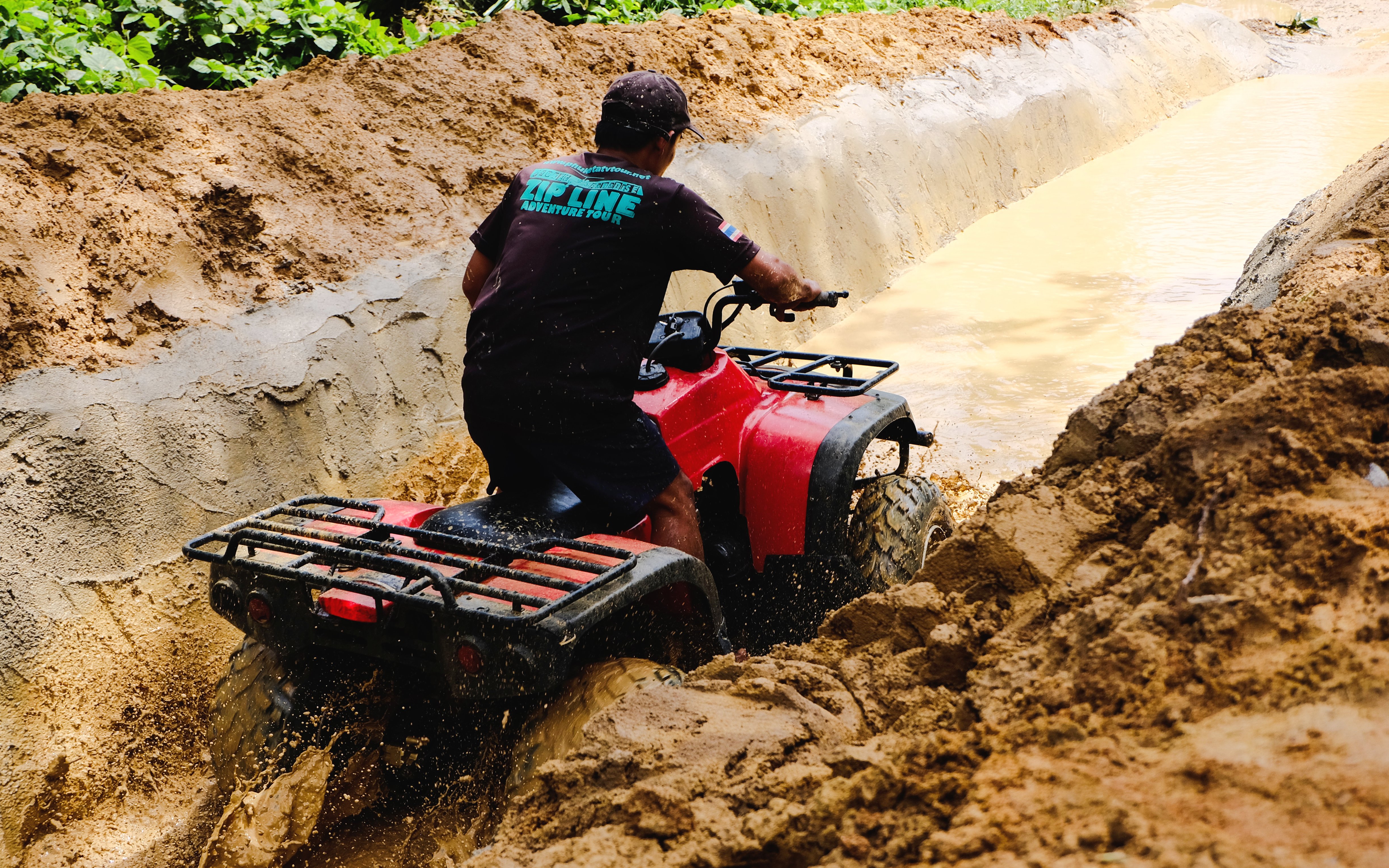 ATV navigating through a muddy trail in a forest setting.