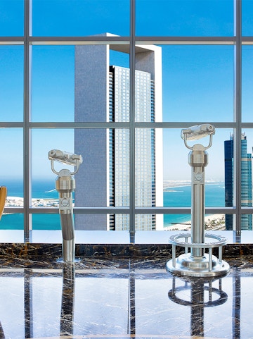 Etihad Tower Observation Deck view with telescopes overlooking Abu Dhabi skyline.