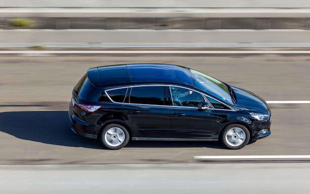 Black minivan on highway for private airport transfer to JFK Airport.