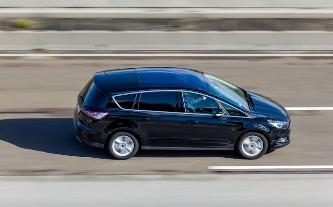 Black minivan on highway for private airport transfer to JFK Airport.