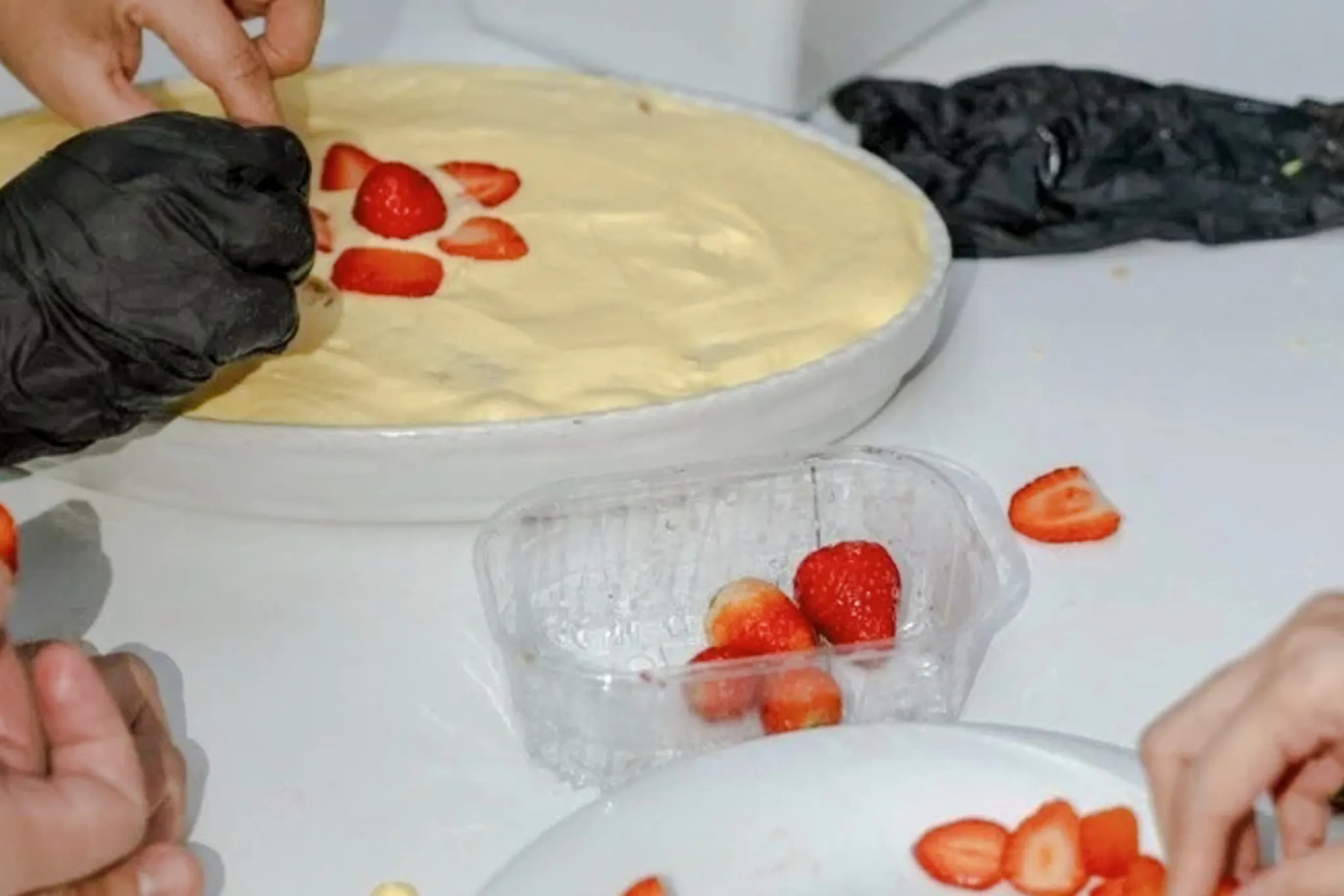 Preparing tiramisu with sliced strawberries in a Florence cooking class.
