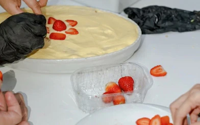 Preparing tiramisu with sliced strawberries in a Florence cooking class.