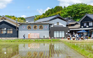 Takeno Sake Brewery in Kyoto with visitors and rice paddies in foreground.