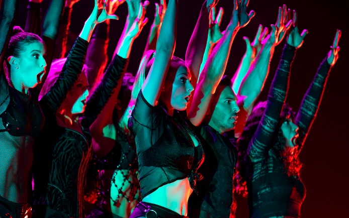 Performers on stage with raised arms during a Chicago show.