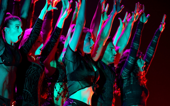 Performers on stage with raised arms during a Chicago show.