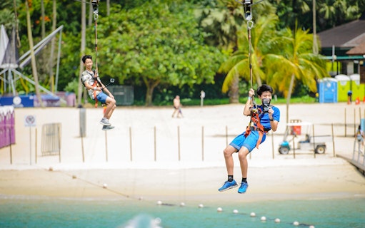 Visitors ziplining over the beach at Mega Adventure Park, Singapore.