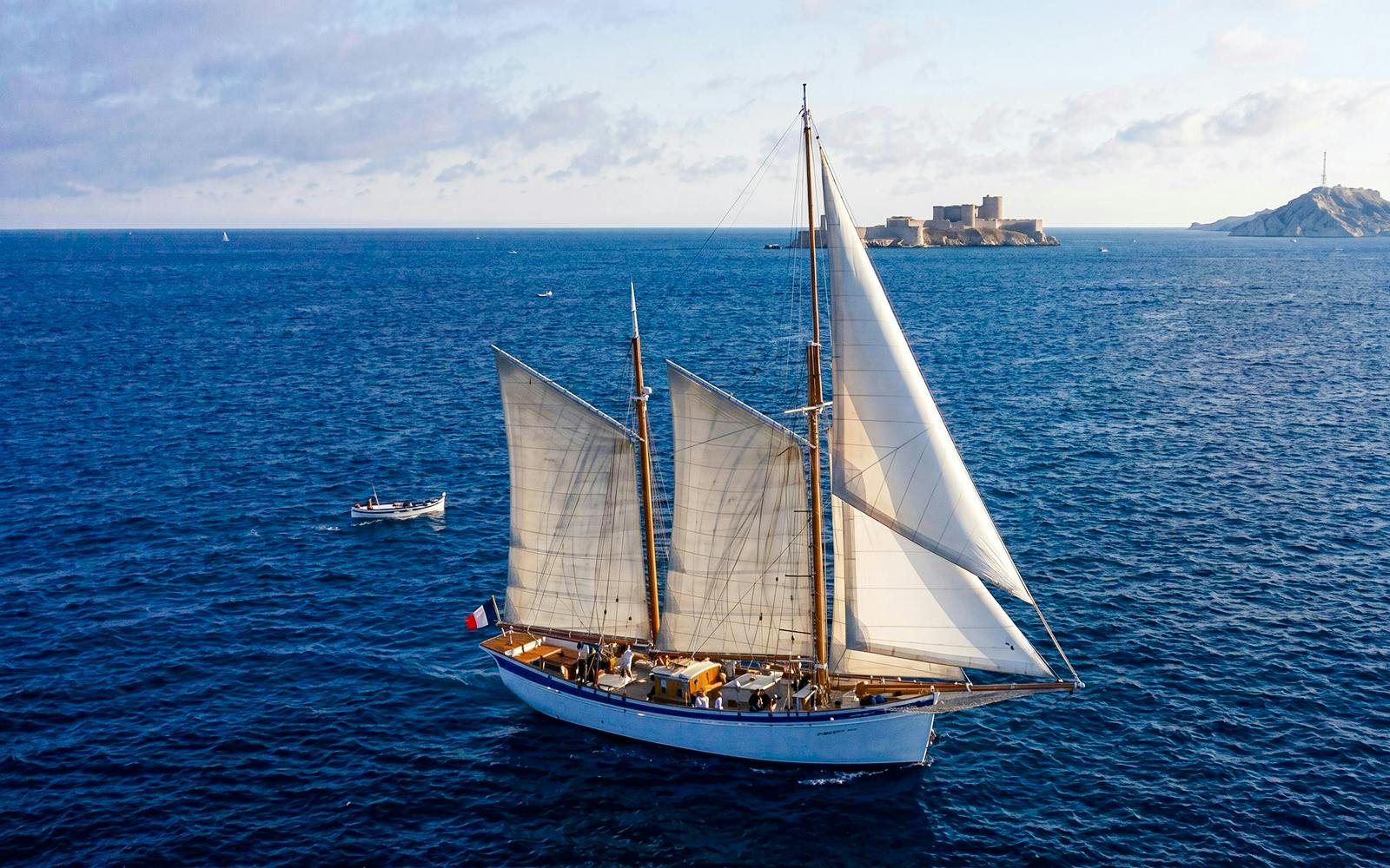 Sailing ship near Calanques with fortress in background, France.