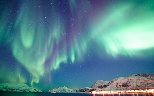 Northern Lights over snowy mountains viewed from a cruise ship.