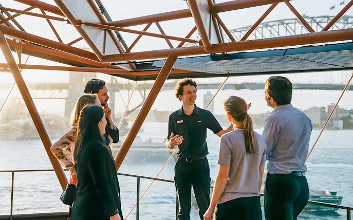 Group on a guided walking tour inside Sydney Opera House with view of Sydney Harbour Bridge.