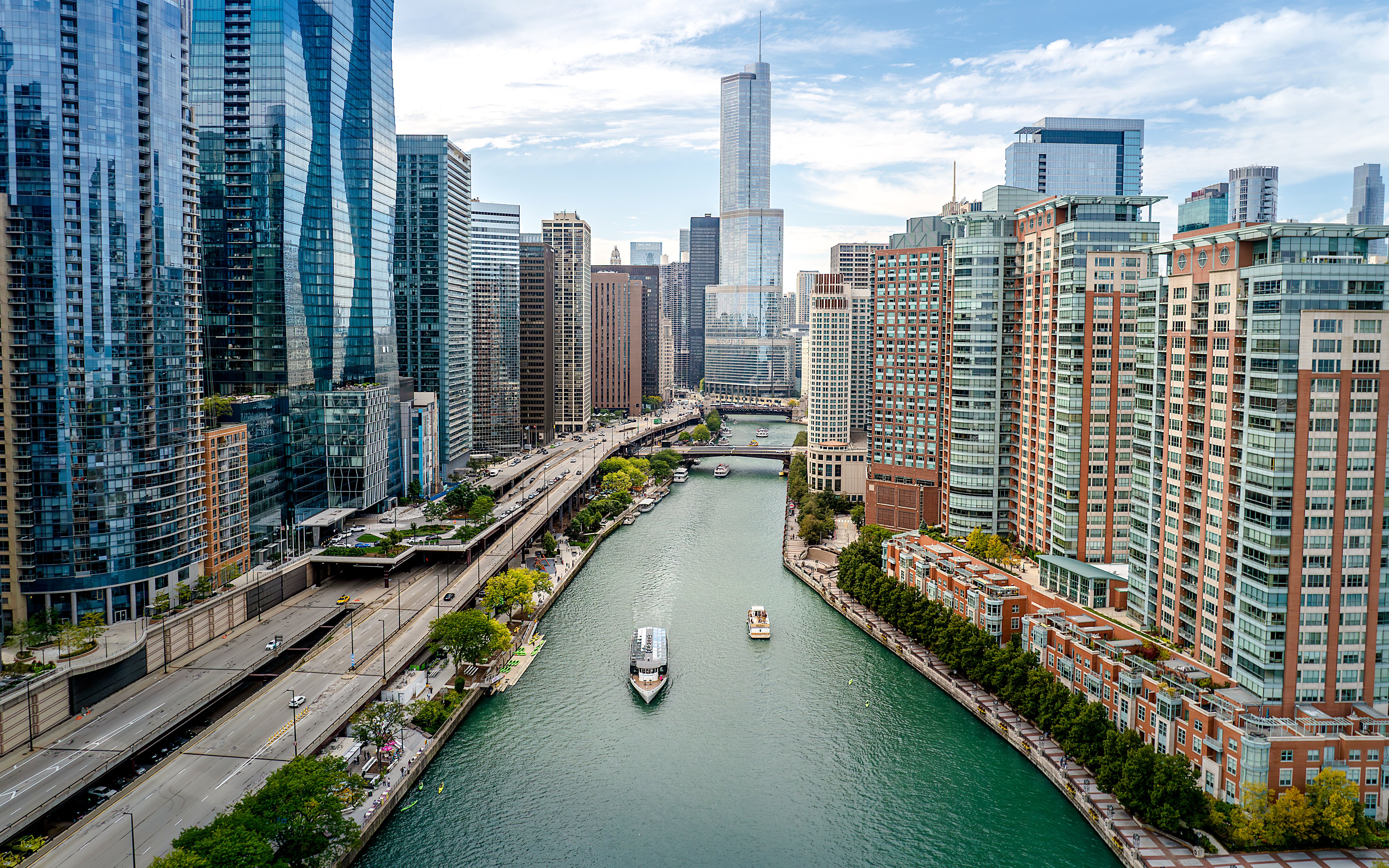 Aerial view of Chicago River with boats and skyscrapers lining the riverbanks.