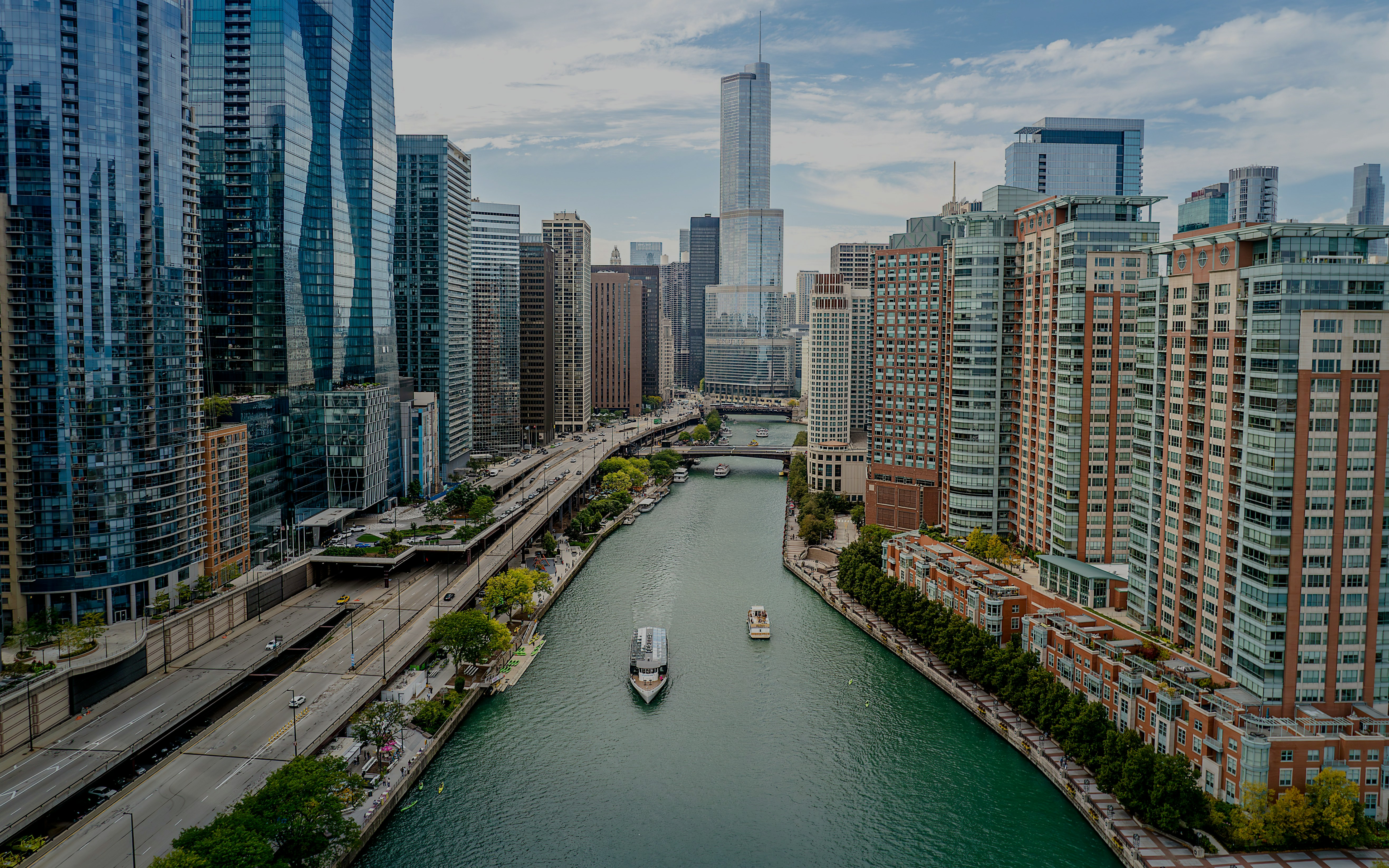 Aerial view of Chicago River with boats and skyscrapers lining the riverbanks.