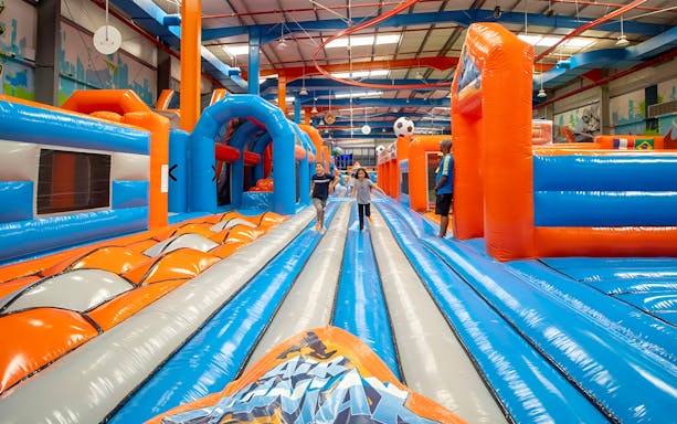 Children running on inflatable obstacle course at Air Maniax Indoor Adventure Park.