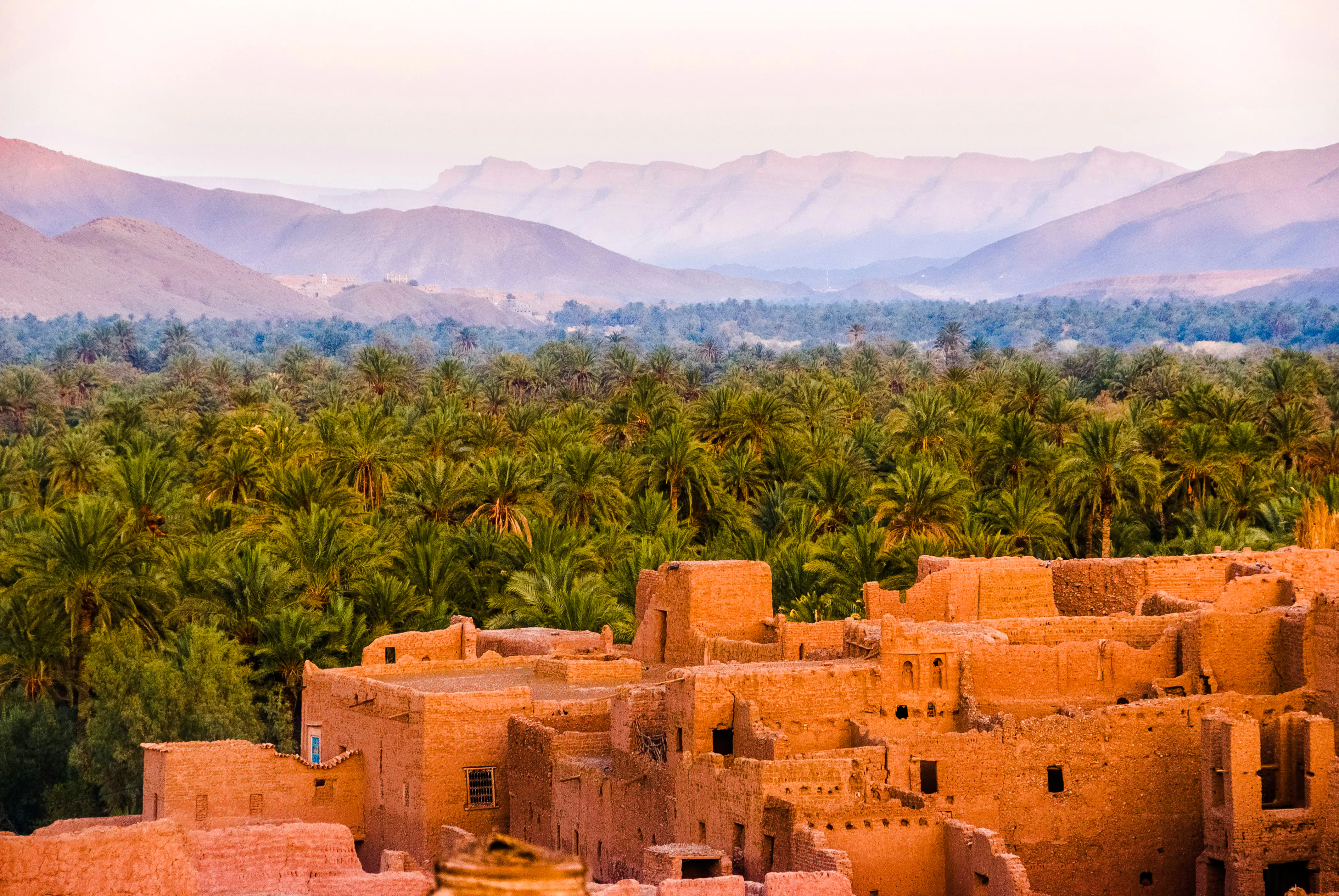 Ancient kasbah with palm grove and Atlas Mountains in Morocco.