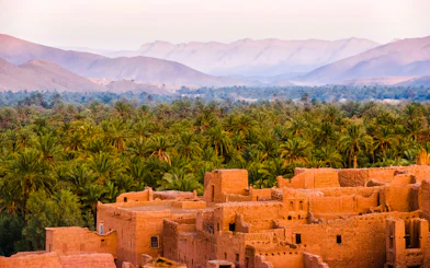 Ancient kasbah with palm grove and Atlas Mountains in Morocco.