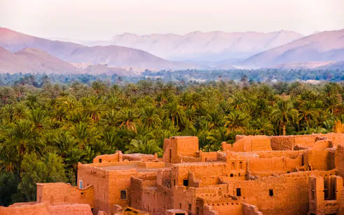 Ancient kasbah with palm grove and Atlas Mountains in Morocco.