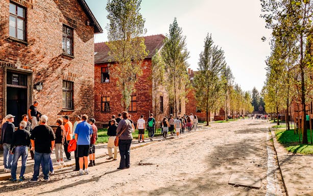 Visitors walking through Auschwitz-Birkenau camp, part of a guided tour in Poland.