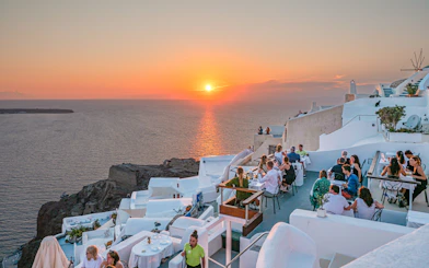 Santorini cliffside dining with sunset view during wine tour.