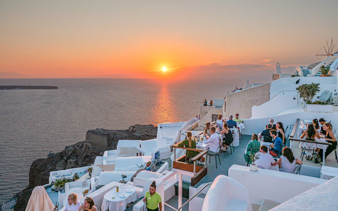 Santorini cliffside dining with sunset view during wine tour.